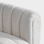 Right facing close up view of the upholstery and inner arm on a contemporary off-white metallic boucle tufted shelter armchair on a white background