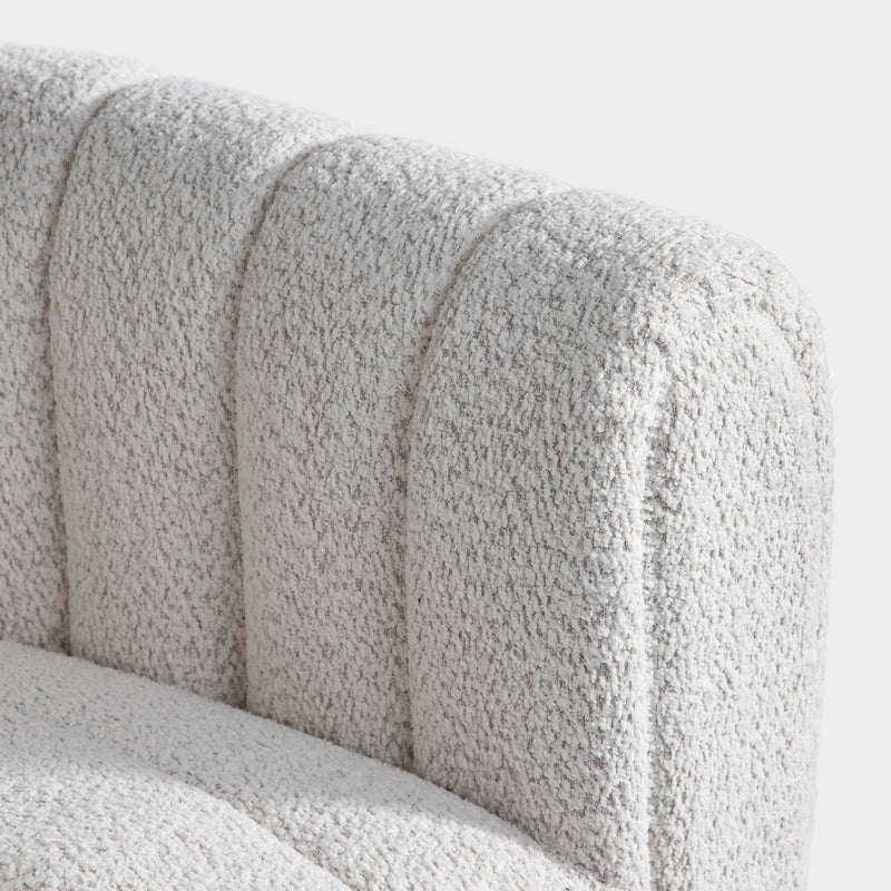 Right facing close up view of the upholstery and inner arm on a contemporary off-white metallic boucle tufted shelter armchair on a white background