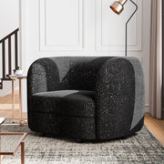 Left facing contemporary black and metallic boucle curved kidney armchair in a living room with accessories