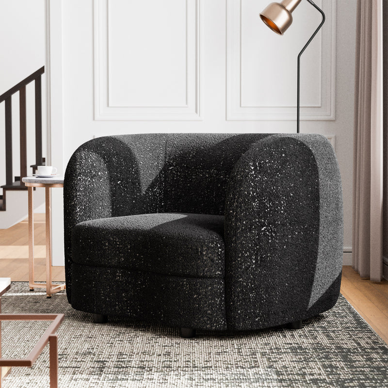 Left facing contemporary black and metallic boucle curved kidney armchair in a living room with accessories