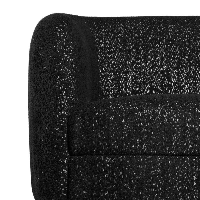 Front facing close up view of the upholstery and armrest on a contemporary black and metallic boucle curved kidney armchair