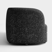 Front facing side view of a contemporary black and metallic boucle curved kidney armchair on a white background