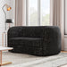Left facing contemporary black and metallic boucle curved kidney loveseat in a living room with accessories