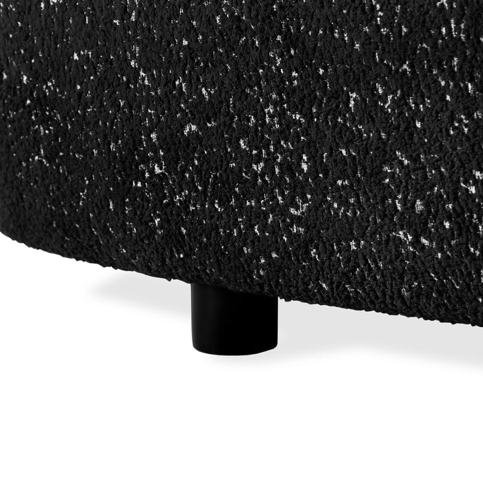 Left facing close up view of the leg on a contemporary black and metallic boucle curved kidney loveseat on a white background