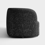 Front facing side view of a contemporary black and metallic boucle curved kidney sofa on a white background