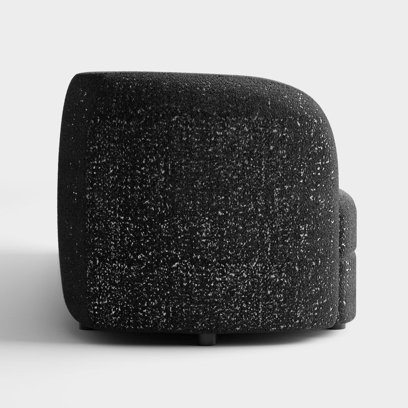 Front facing side view of a contemporary black and metallic boucle curved kidney sofa on a white background