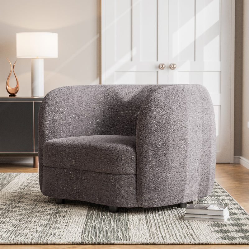 Left facing contemporary charcoal gray and metallic boucle curved kidney armchair in a room with accessories
