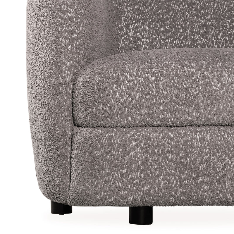 Front facing close up view of the upholstery and leg on a contemporary charcoal gray and metallic boucle curved kidney armchair on a white background
