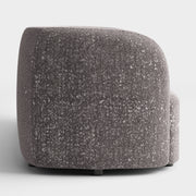 Front facing side view of a contemporary charcoal gray and metallic boucle curved kidney armchair on a white background