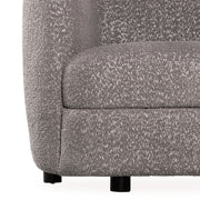 Front facing close up view of the upholstery and leg on a contemporary charcoal gray and metallic boucle curved kidney sofa on a white background