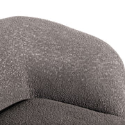 Right facing close up view of the inner armrest on a contemporary charcoal gray and metallic boucle curved kidney sofa on a white background
