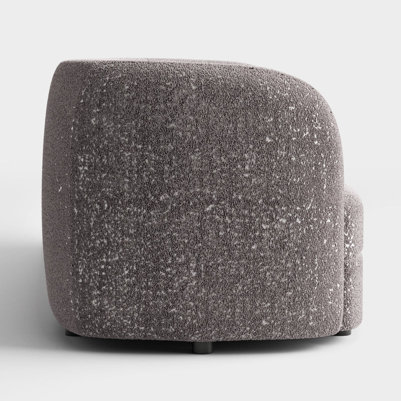 Front facing side view of a contemporary charcoal gray and metallic boucle curved kidney sofa on a white background