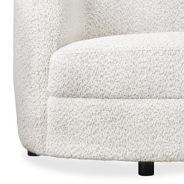 Front facing close up view of the upholstery and leg on a contemporary off-white metallic boucle curved kidney armchair on a white background