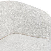 Right facing close up view of the inner armrest on a contemporary off-white metallic boucle curved kidney armchair on a white background