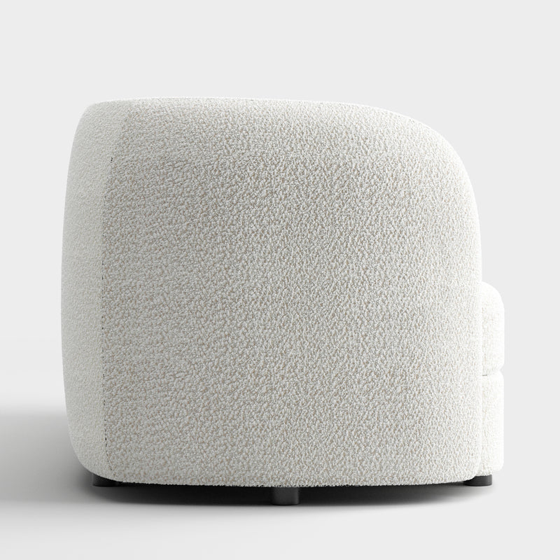 Front facing side view of a contemporary off-white metallic boucle curved kidney armchair on a white background