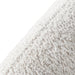 Right facing close up view of the upholstery and back on a contemporary off-white metallic boucle curved kidney loveseat on a white background