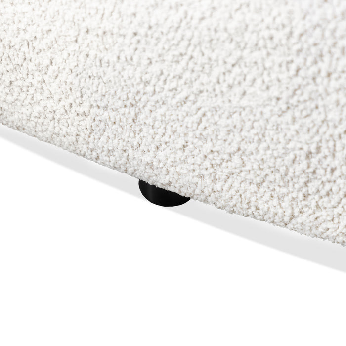 Left facing close up view of the leg on a contemporary off-white metallic boucle curved kidney loveseat on a white background