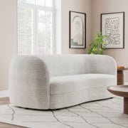 Right facing contemporary off-white metallic boucle curved kidney sofa in a room with accessories
