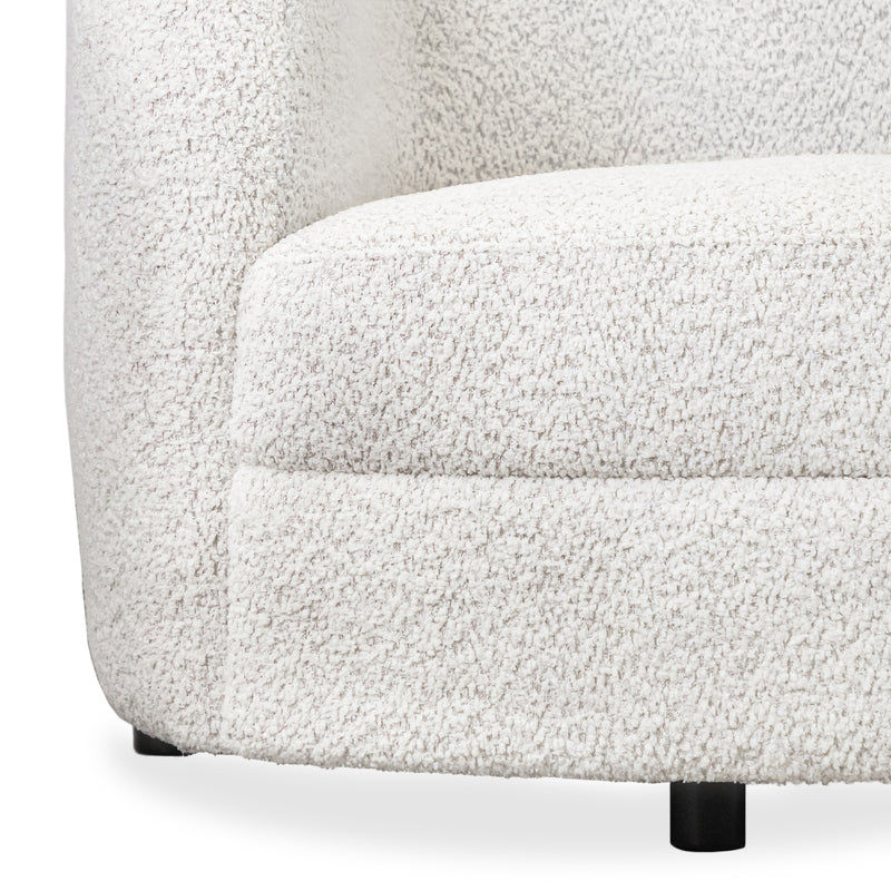 Front facing close up view of the upholstery and leg on a contemporary off-white metallic boucle curved kidney sofa on a white background