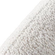 Right facing close up view of the upholstery and back on a contemporary off-white metallic boucle curved kidney sofa on a white background