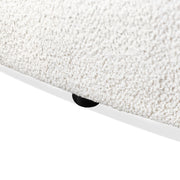 Left facing close up view of the leg on a contemporary off-white metallic boucle curved kidney sofa on a white background