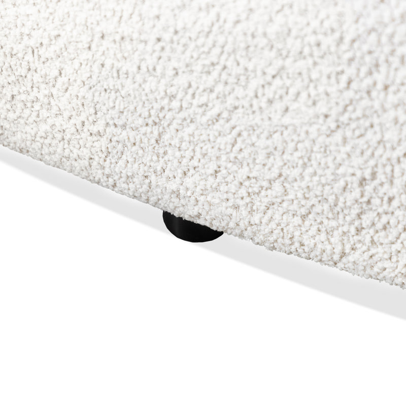 Left facing close up view of the leg on a contemporary off-white metallic boucle curved kidney sofa on a white background