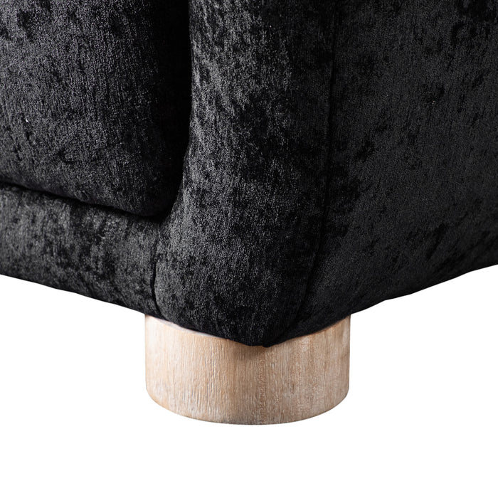 Left facing close up view of the leg on a contemporary black chenille sloping tuxedo accent armchair on a white background