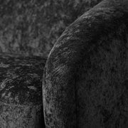 Left facing close up view of the upholstery and armrest on a contemporary black chenille sloping tuxedo loveseat