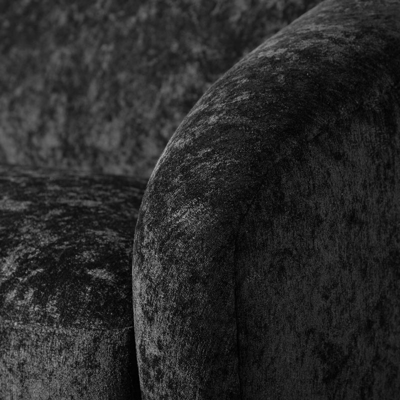 Left facing close up view of the upholstery and armrest on a contemporary black chenille sloping tuxedo loveseat
