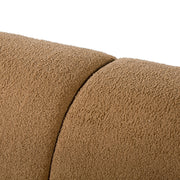 Left facing close up view of the upholstery and backrest on a contemporary brown chenille sloping tuxedo loveseat on a white background