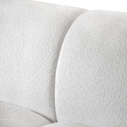 Left facing close up view of the upholstery and backrest on a contemporary brown chenille sloping tuxedo loveseat on a white background