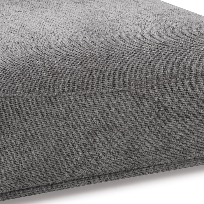 Right facing close up of the seat of a contemporary grey chenille trapezoidal armless chair with an adjustable back on a white background