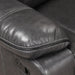 Right facing close up of the pillowtop armrest of a transitional dark grey faux leather reclining sectional sofa with a storage console on a white background