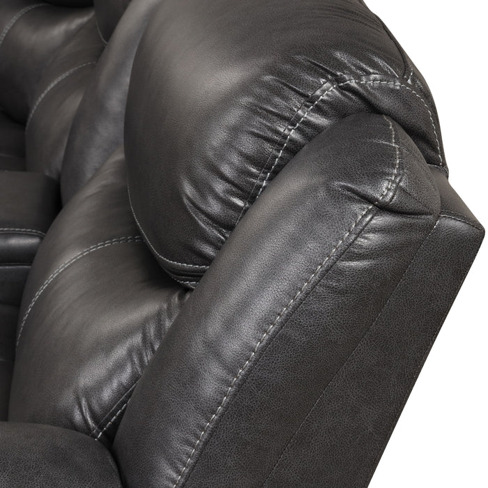 Left facing close up of the backrest of a transitional dark grey faux leather reclining sectional sofa with a storage console on a white background