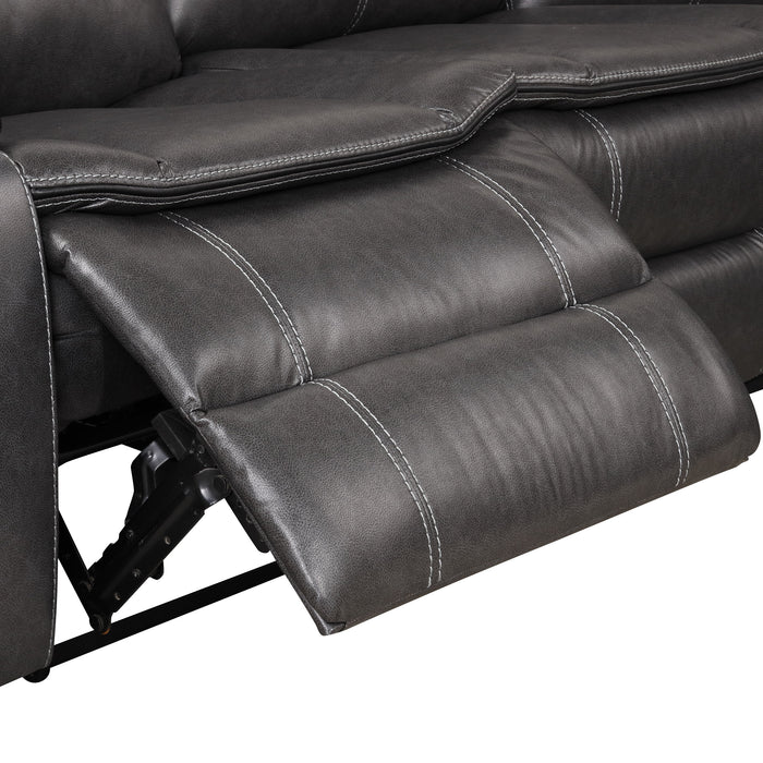Right facing close up of the extended leg rest of a transitional dark grey faux leather reclining sectional sofa with a storage console on a white background