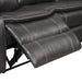 Right facing close up of the extended leg rest of a transitional dark grey faux leather reclining sectional sofa with a storage console on a white background