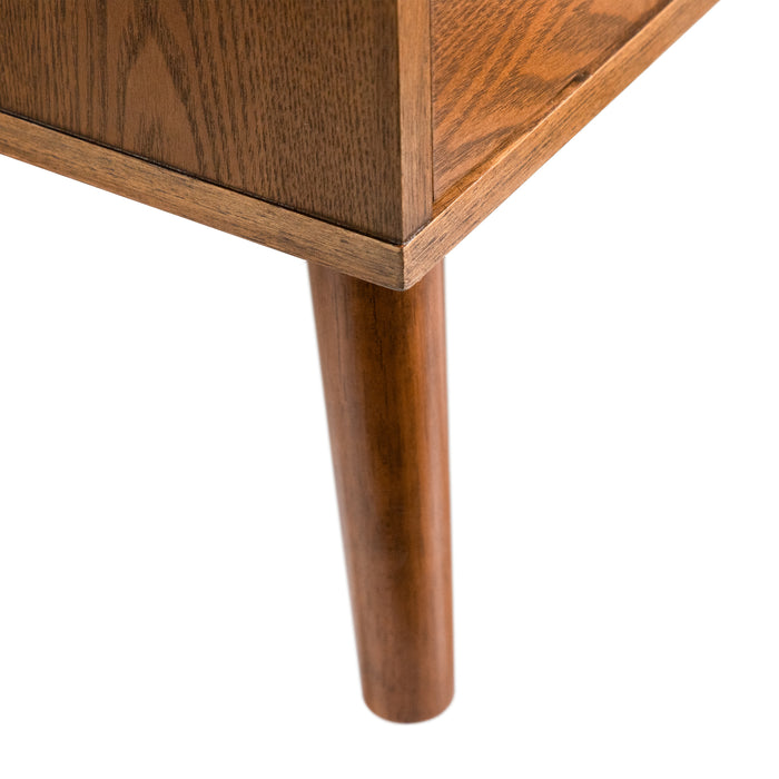 Right facing close up view of the corner and splayed leg on a mid-century modern walnut finish two-drawer nightstand on a white background