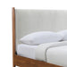 Left facing close up view of the headboard on a mid-century modern walnut finish and beige boucle queen bed on a white background