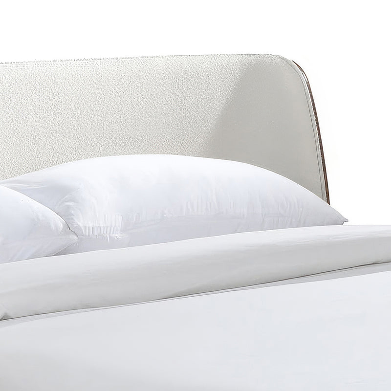 Right facing close up view of the headboard on a mid-century modern walnut and beige boucle wingback queen bed on a white background