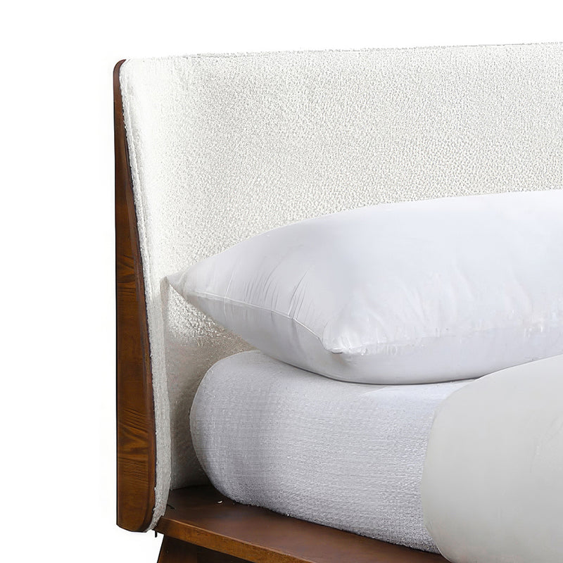 Right facing close up view of the headboard on a mid-century modern walnut and beige boucle wingback queen bed on a white background