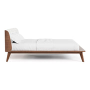 Front facing side view of a mid-century modern walnut and beige boucle wingback queen bed on a white background