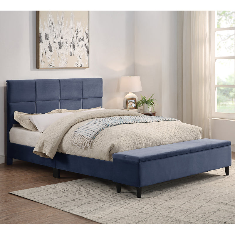 Right facing contemporary grey upholstered full bed with attached storage bench in a room with linens and accessories
