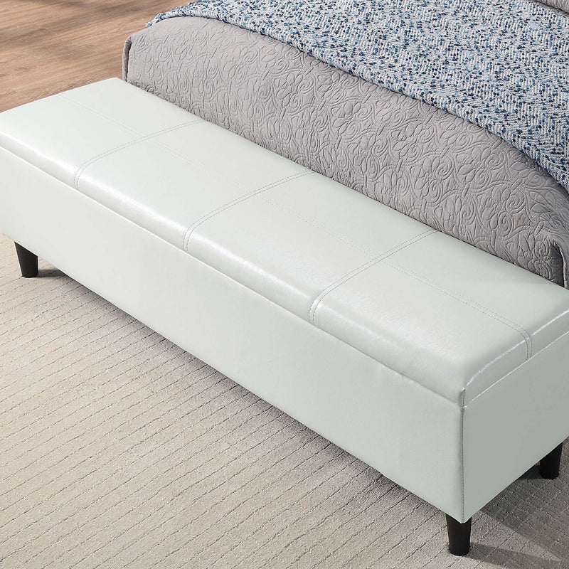 Left facing close up of the closed storage bench on a contemporary white upholstered full bed with attached storage bench in a room with linens and accessories