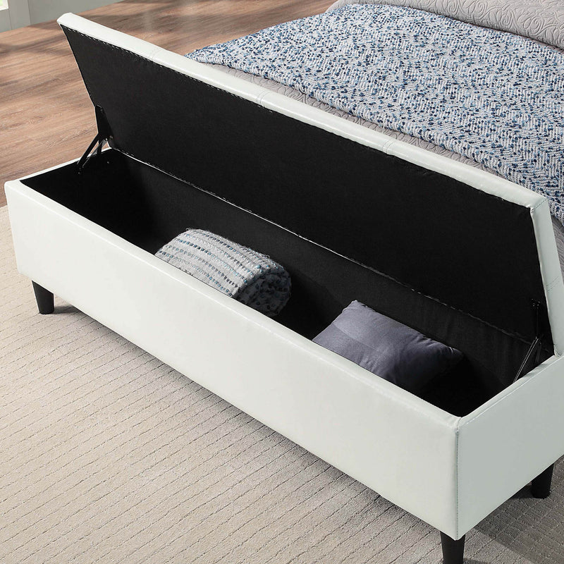 Left facing close up of the open storage bench on a contemporary white upholstered full bed with attached storage bench in a room with linens and accessories
