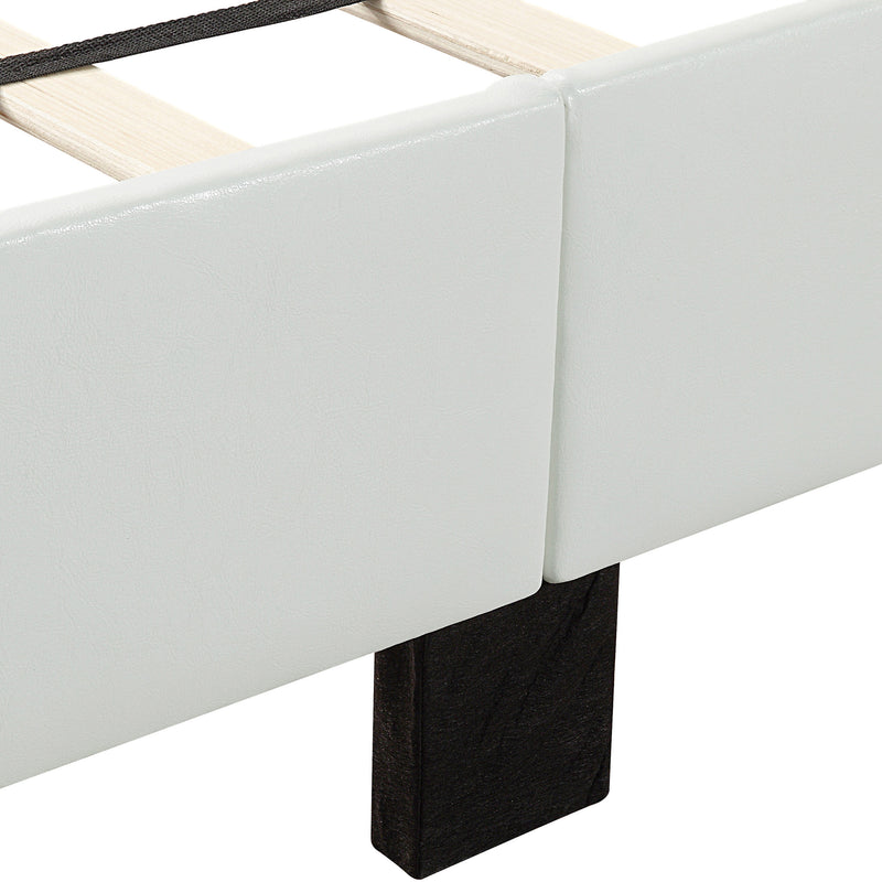 Left facing close up of the upholstered rail and wooden leg on a contemporary white upholstered full bed with attached storage bench on a white background