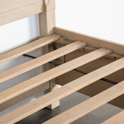 Right facing close up of the support slats on a transitional light oak eastern king platform bed with two storage drawers, on a white background