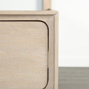Front facing close up of the footboard drawer corner on a transitional light oak eastern king platform bed with two storage drawers, in a room