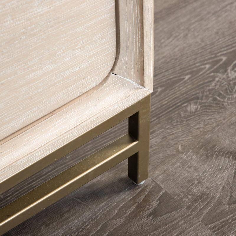 Right facing close up of the metal base on a transitional light oak eastern king platform bed with two storage drawers, in a room