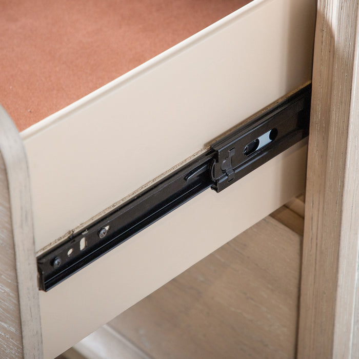 Left facing close up of the ball-bearing glides on a transitional light oak two-drawer nightstand with a metal base