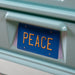 Angled close up of the Peace license plate on a vintage teal peace bus novelty kid's platform bed